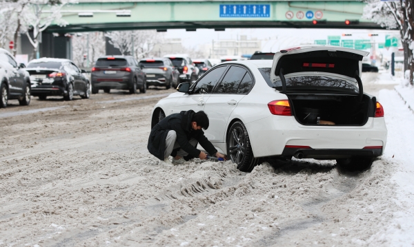 대설특보가 발령된 18일 광주 서구 한 도로에서 한 시민이 차량 아래에 쌓인 눈을 치우고 있다. 사진=연합뉴스