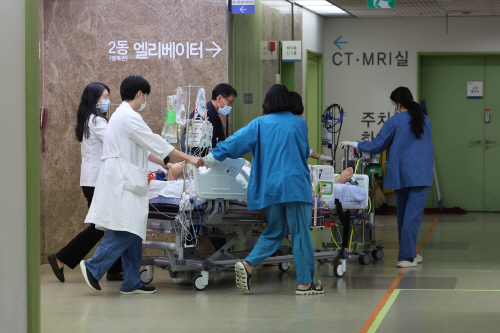 정부가 보건의료재난 위기경보를 최상위 단계인 '심각'으로 상향한 23일 서울의 한 대학병원에서 병원관계자가 환자를 옮기고 있다. 사진=연합뉴스